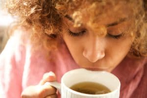 Close up young black woman drinking cup of tea