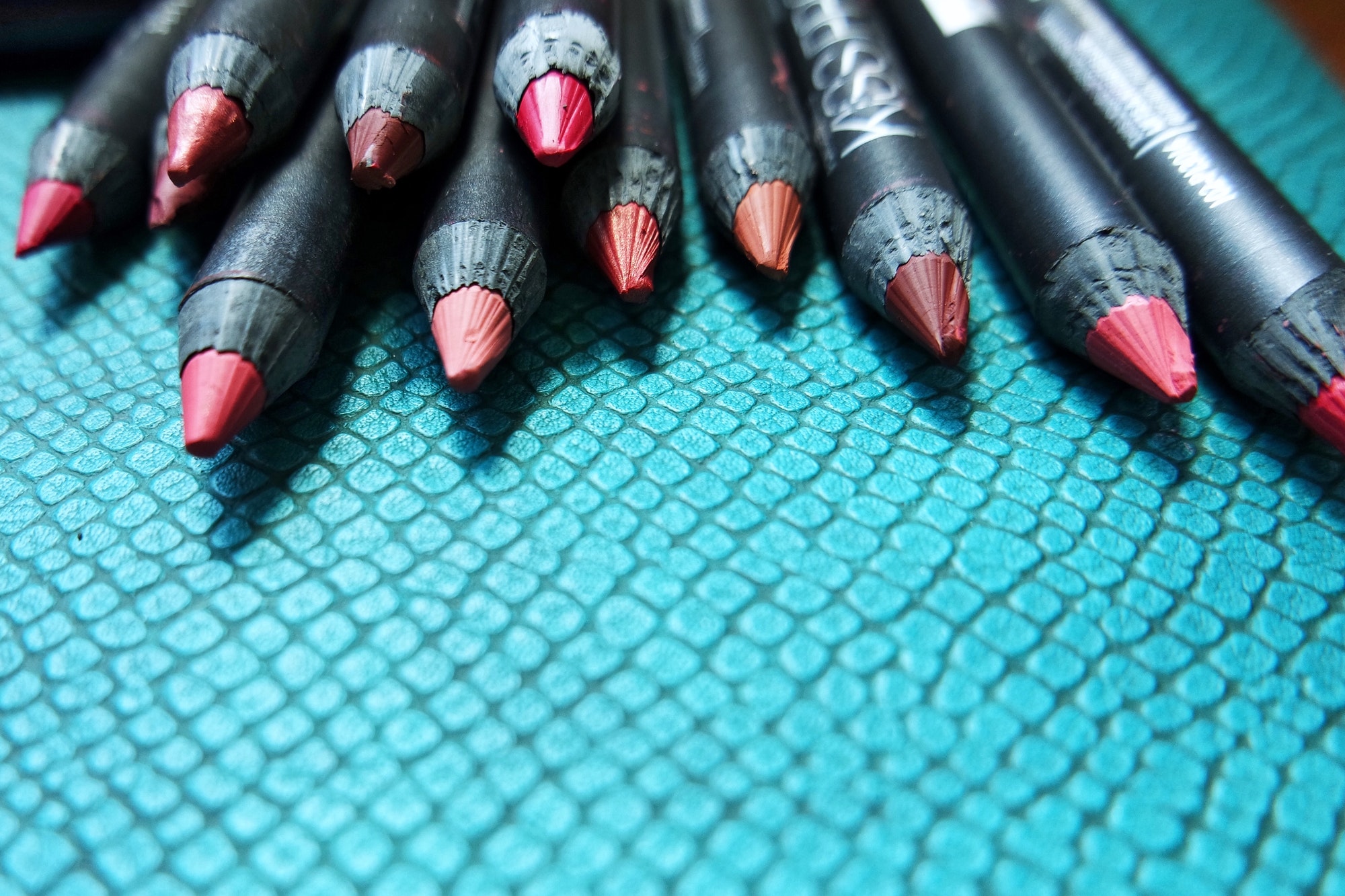 Lip pencils on a turquoise make up bag.