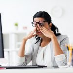 businesswoman rubbing tired eyes at office