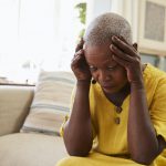 Senior Woman Sitting On Sofa At Home Suffering From Depression