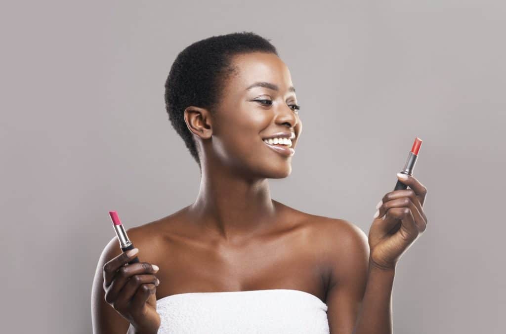 African american woman choosing between two lipstick colors