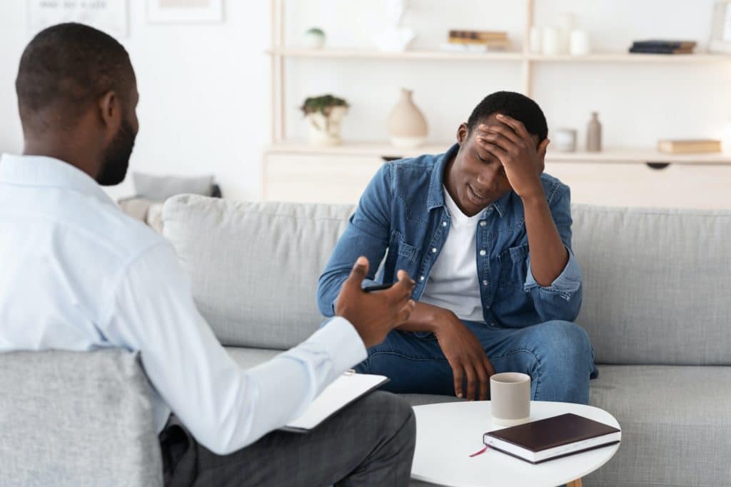 Psychotherapy Concept. Depressed black man talking to psychologist during individual therapy