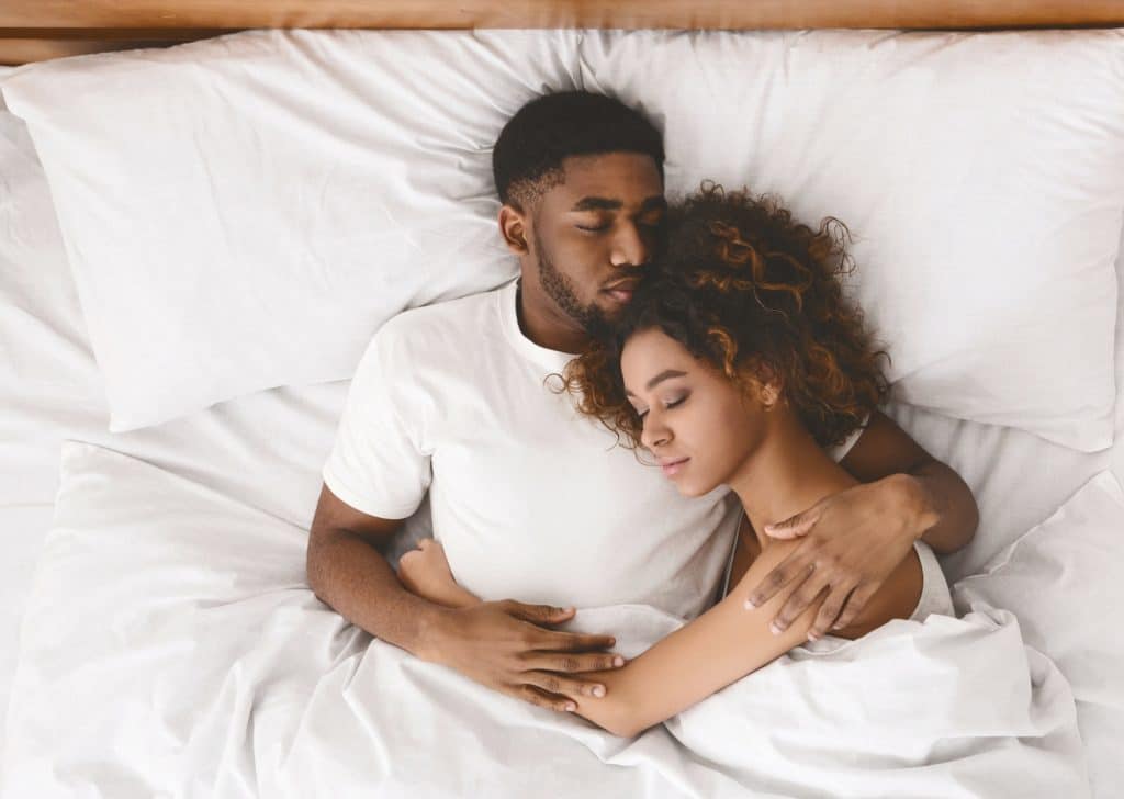 Young black couple sleeping together in bed