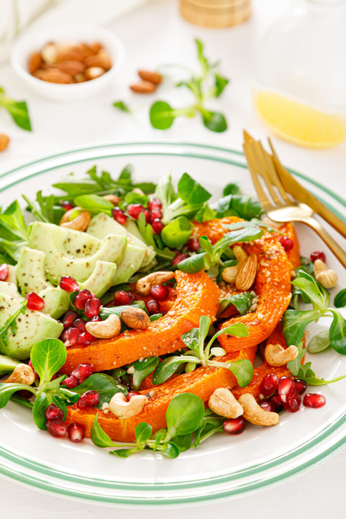 Fresh vegetable salad with pumpkin, avocado, pomegranate and nuts